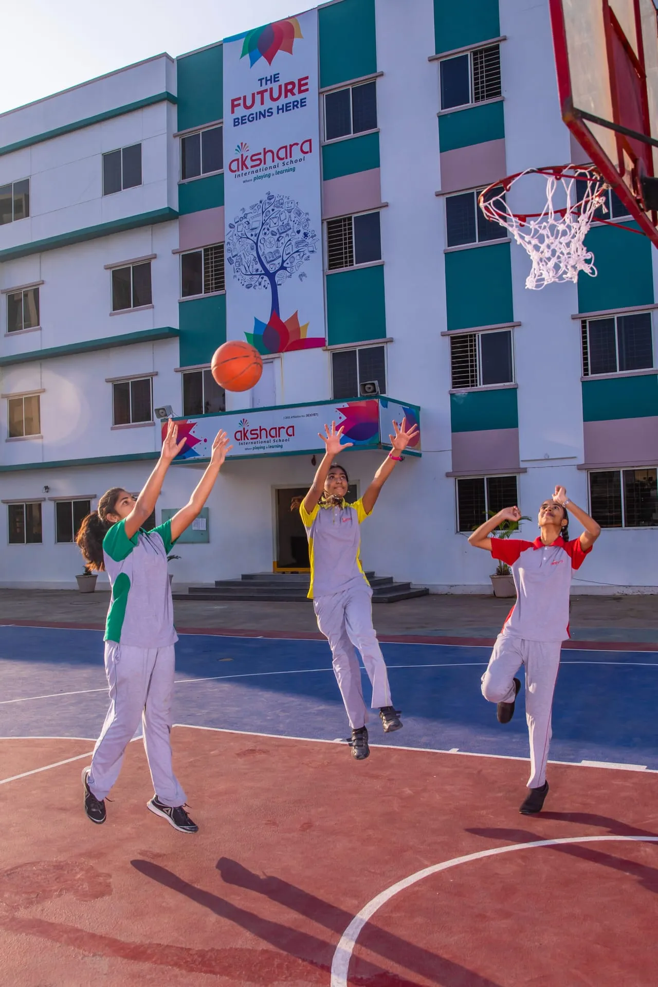 Girls practising basketball in front of the school building