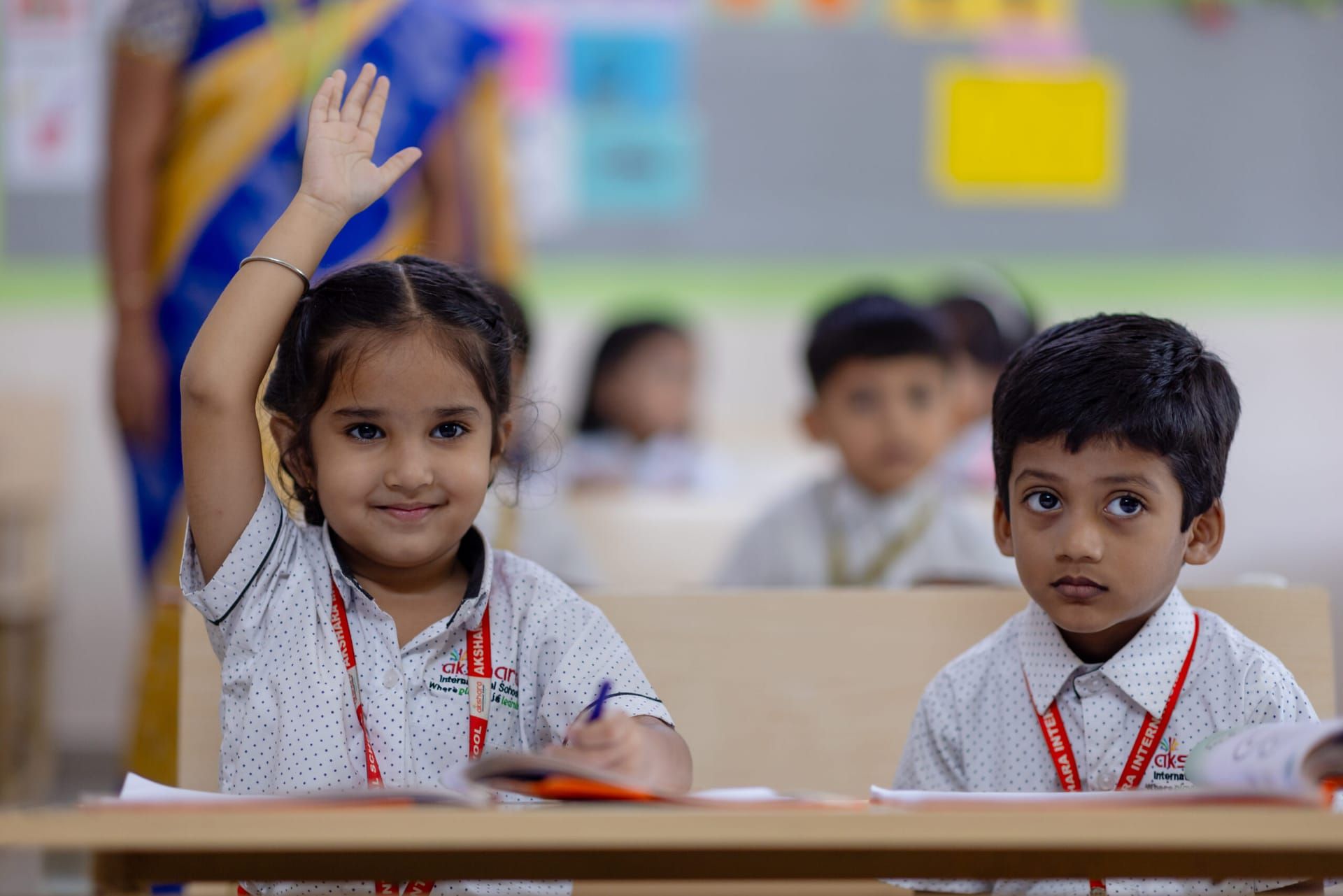 Pre-primary children raising their hands in an Akshara classroom