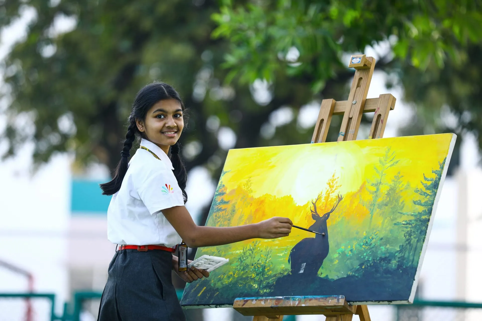 Akshara student painting a landscape on an easel outdoors