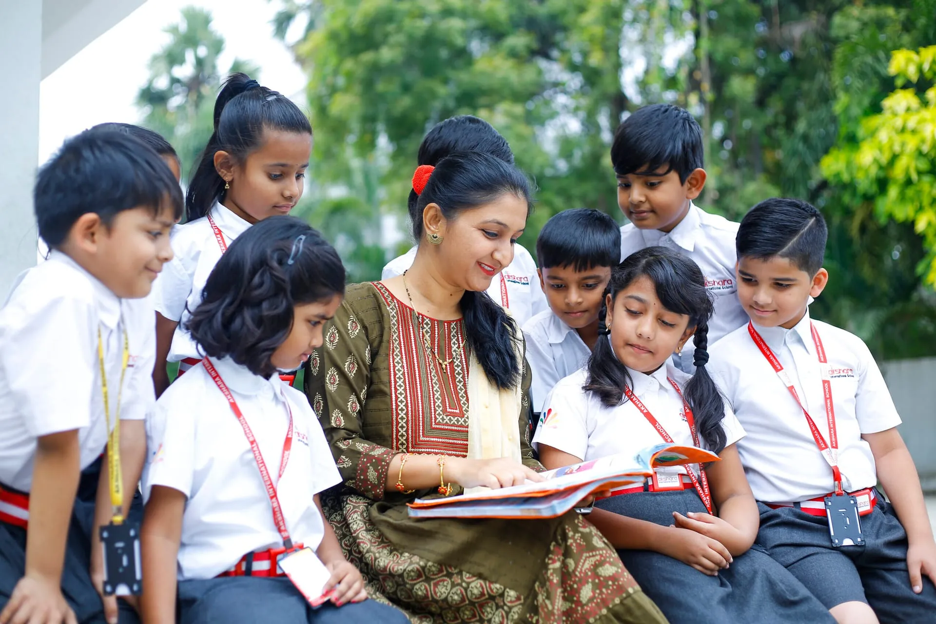 Teacher reading a story with a group of Akshara children outdoors
