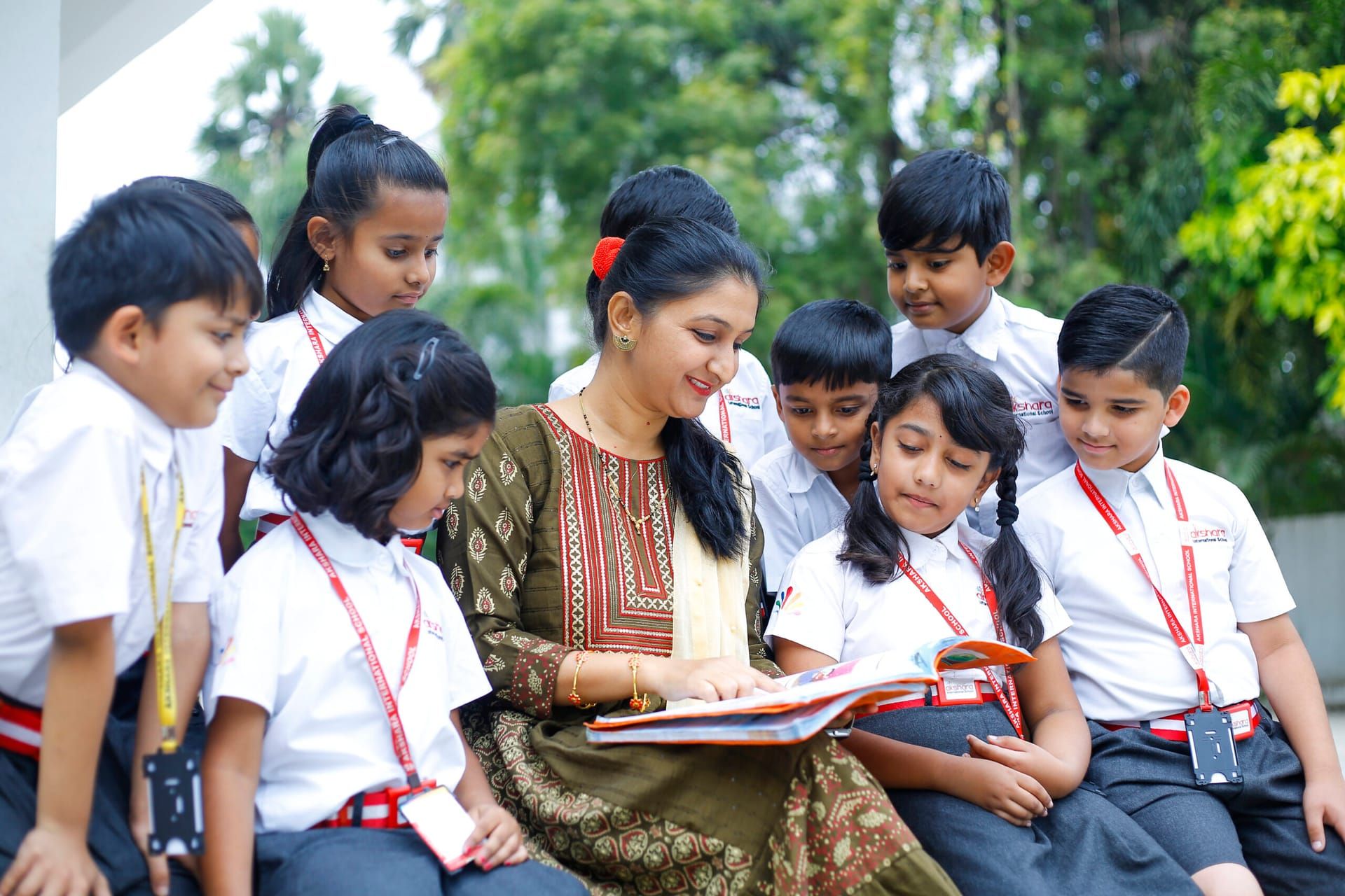 Teacher reading a story with a group of Akshara children outdoors