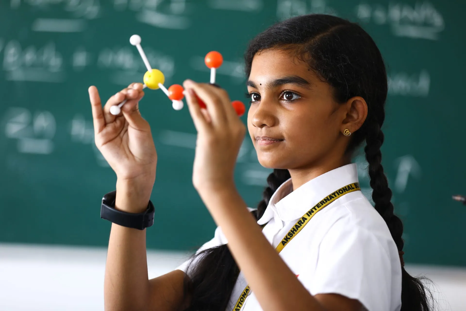 Middle school student studying a molecular model in class